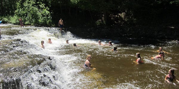 people swimming in a shallow waterfall